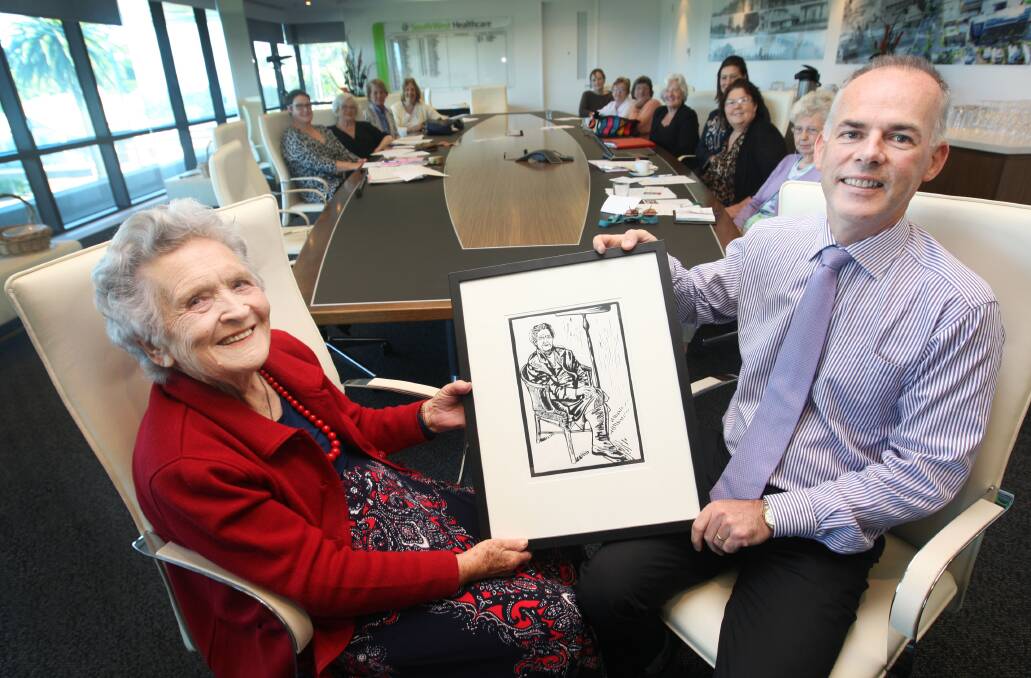 South West Healthcare CEO John Krygger presents Iris Bickley with a lino-cut print of herself as a gift for her long service to the base hospital. 