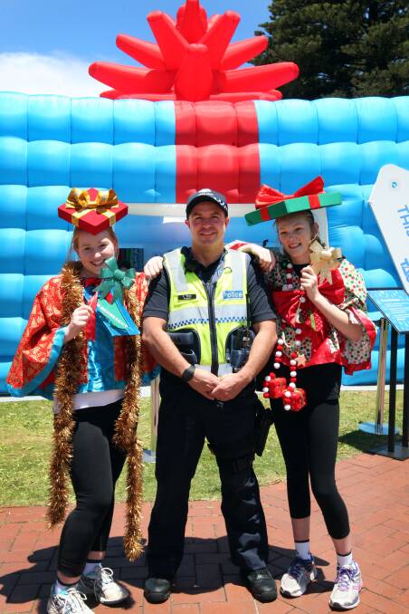In front of the TAC Be Present this Christmas display are (from left) Shannara Drake, 15, Sergeant Cameron Ross, and Meg Dean, 13, all from Warrnambool. 141219LP14 Picture: LEANNE  PICKETT