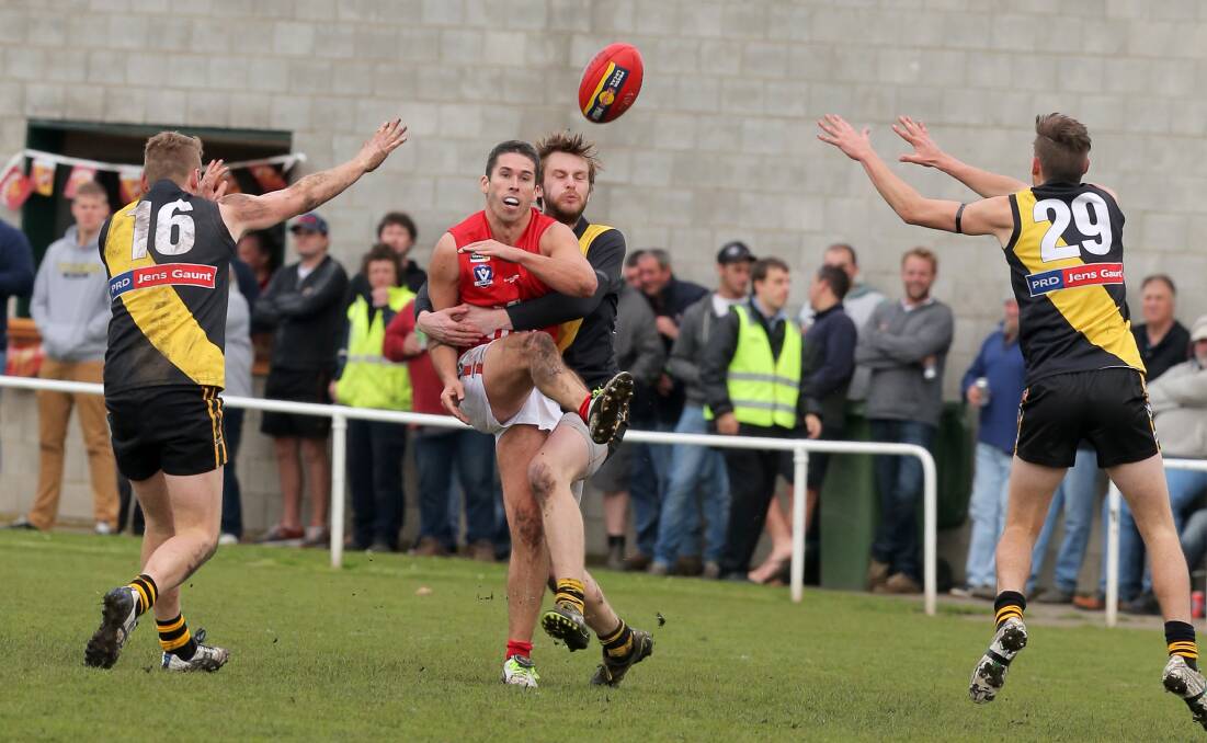 Dennington’s Dustin McCorkell gets a kick away despite the tackle of Merrivale’s Claye Cassidy and outstretched arms of Brad Kelly (left) and Lachlan Kelly. 140816RG29 Picture: ROB GUNSTONE