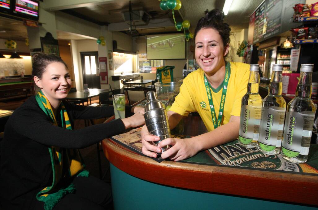 Sharney Parker (left) samples the Brazilian drink ‘caipirinha’ served by the Cally Hotel’s Hannah Oates as they gear up for the broadcast of the Socceroos’ first World Cup game at 8am on Saturday morning.  140610VH11 Picture: VICKY HUGHSON