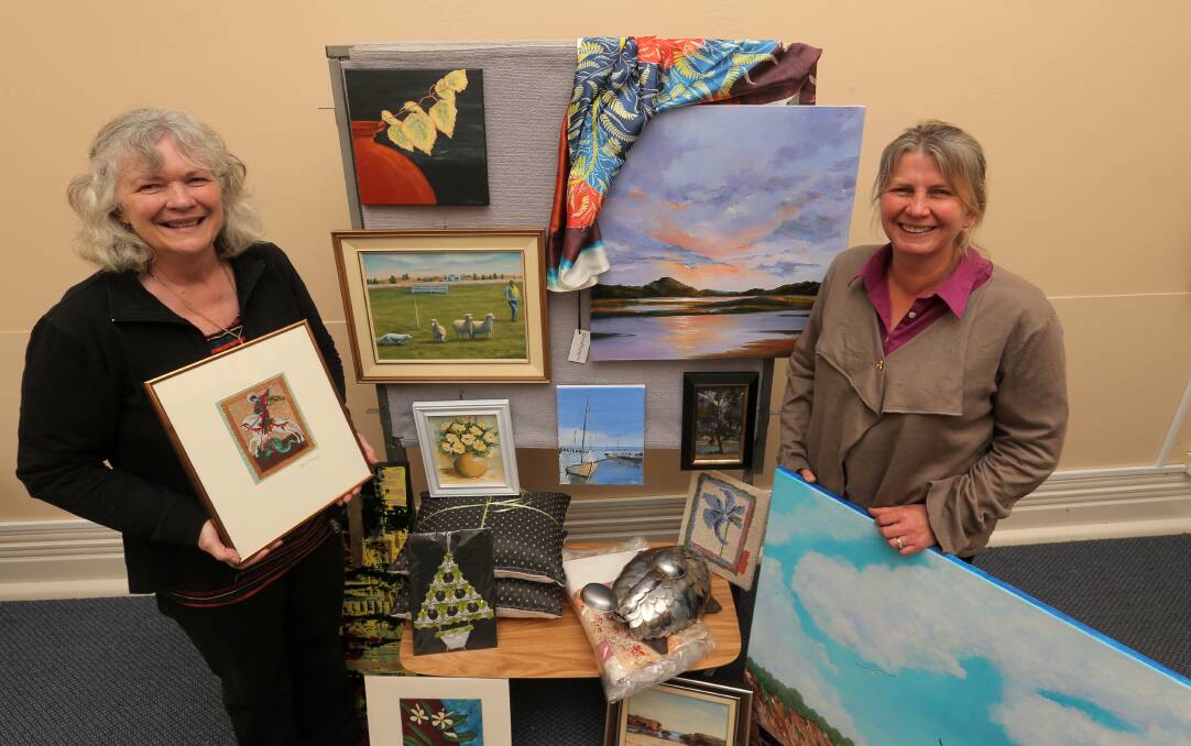 Assistant priest Robyn Shackell (left) and Anglicare’s community development co-ordinator Louise Serra with some of the donated artworks up for auction. 141023VH14 Picture: VICKY HUGHSON