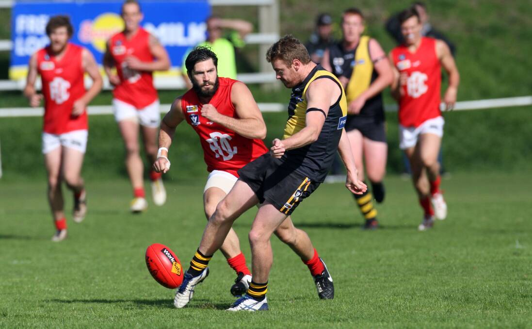 Brad Kelly kicks clear for Merrivale as Dennington’s Chris Vickery arrives too late during Saturday’s 46-point win by the Tigers. Picture: LEANNE PICKETT