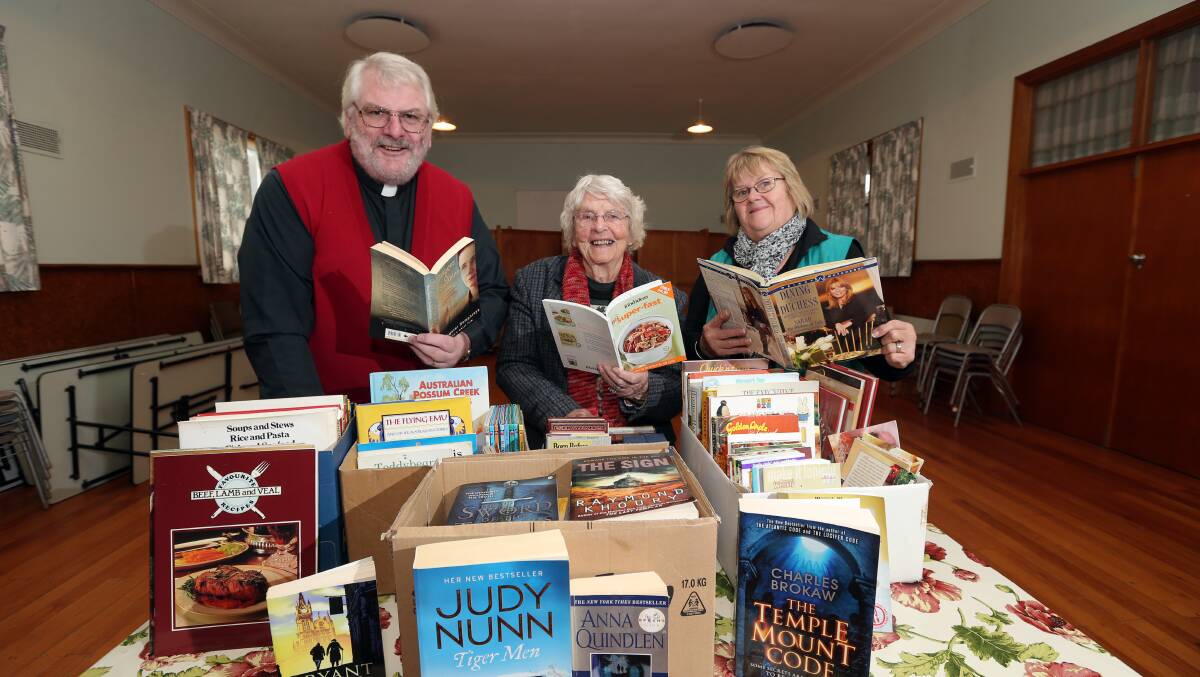 Father Geoffrey Humble, Marj Almond and Margy Blain organise some of the hundreds of books to be offered for sale at this weekend’s fund-raising sale in the church hall. 150520DW21 Picture: DAMIAN WHITE