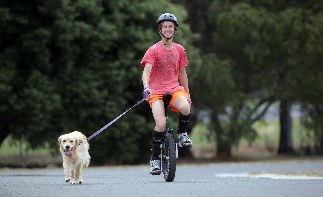 Bushfield’s Alex Jones, 17, takes Annie for some exercise — or vice versa — on his unicycle. 141221DW70 Picture: DAMIAN WHITE