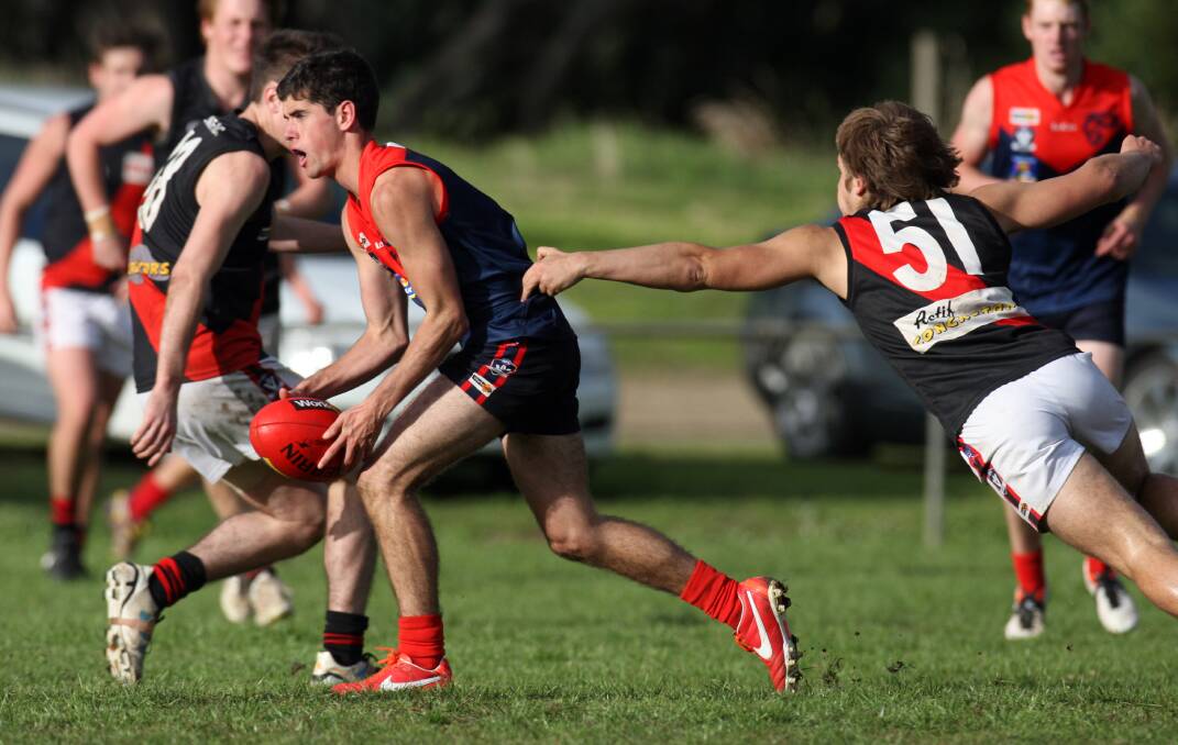 East Warrnambool’s Shaun Brown (right) lunges to stop the Demons’ ball carrier Ben Saunders.  Pictures: LEANNE PICKETT
