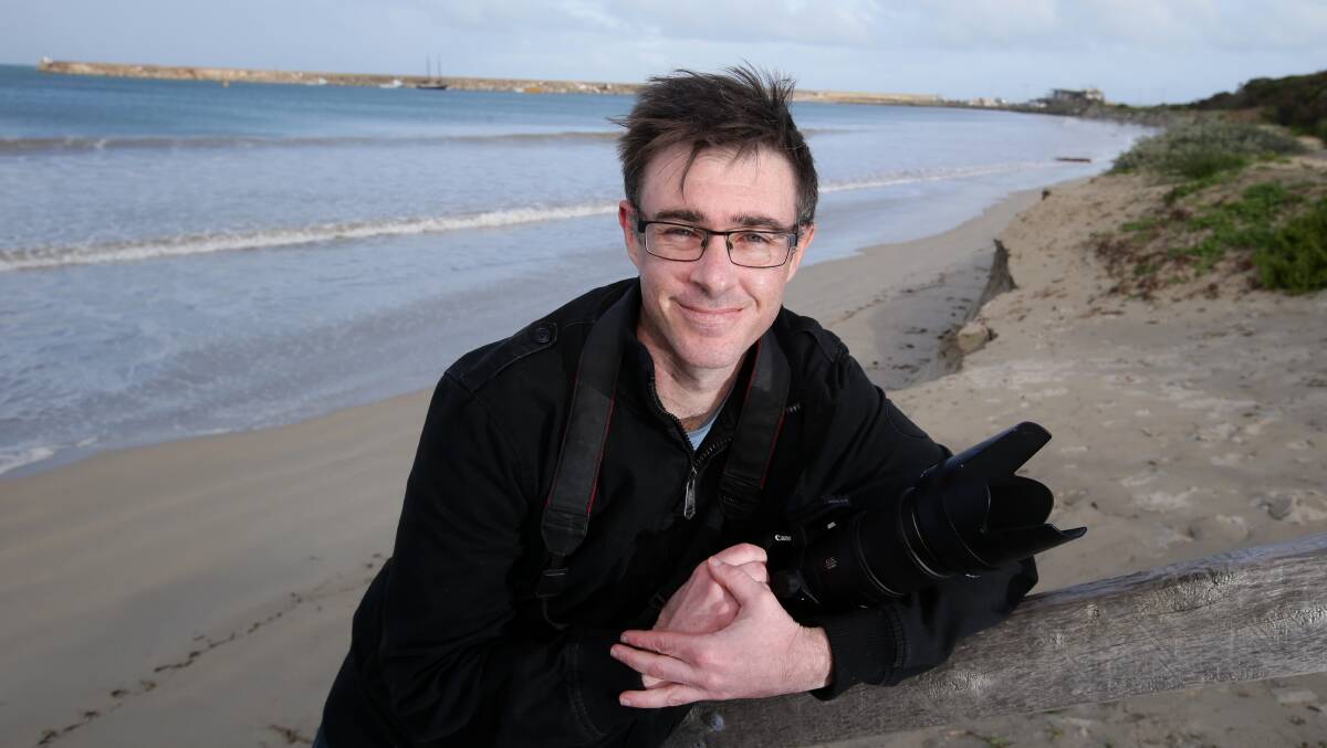 Warrnambool photographer Dan Atkinson with a much calmer Lady Bay in the background, compared to the spectacular image he captured of the breakwater on Tuesday (inset).  