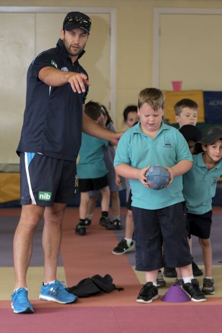 Jimmy Bartel instructs Warrnambool West Primary student Cody Welsh, 7.