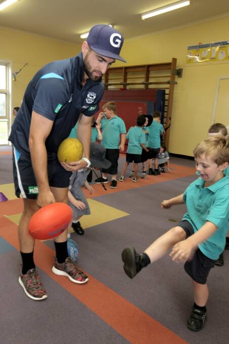 Geelong player Chane Kersten instructs Warrnambool West Primary student Declan Carter, 6.