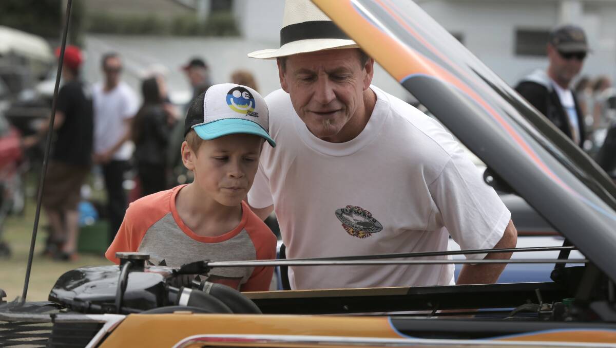 Eli Fahey, 10, and his grandfather Martin Dunstan, both of Warrnambool, examine the engine of a street rod. 