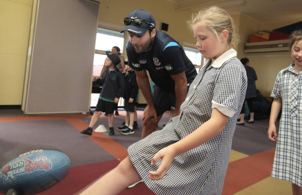 Jimmy Bartel instructs Warrnambool West Primary student Hayley Halliwell, 9, during a visit to the school. 