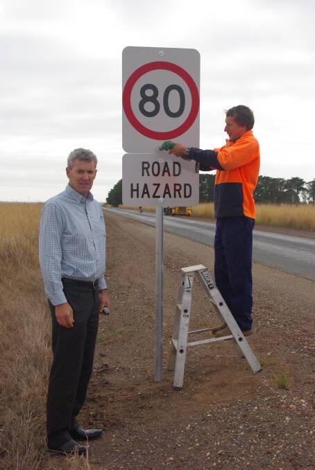 Corangamite Shire mayor Chris O’Connor inspects one of the new 80km/h signs installed on Foxhow Road.