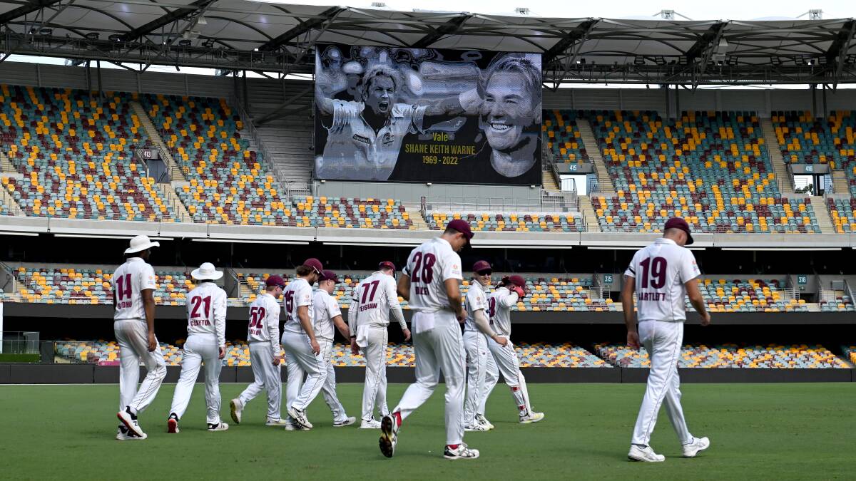 Queensland players walk on to the field after tea at the Gabba wearing black armbands in tribute to Shane Warne. Picture: Getty Images