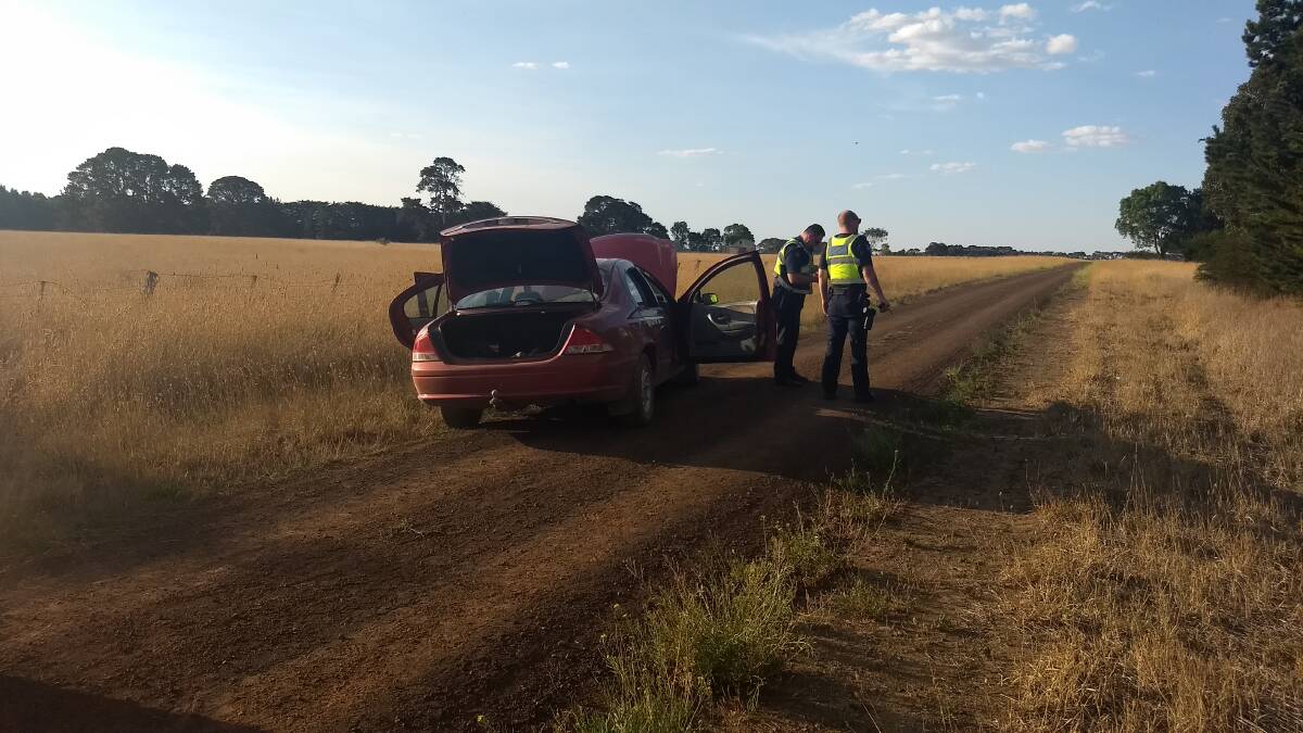 Caught: Police officers with the maroon 2000 Ford Fairmont sedan after it ran out of fuel near Caramut on Saturday evening.