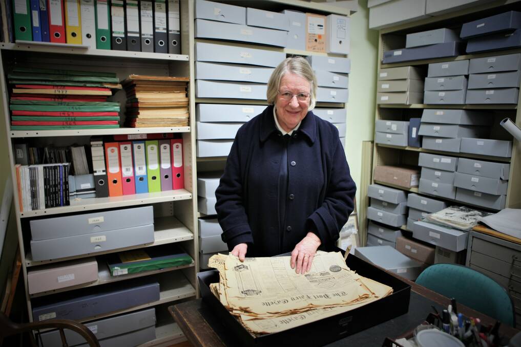 CRAMPED: Port Fairy Historical Society president Judith Kershaw looks through some old newspapers. She is hoping a new room will give members more space to work.