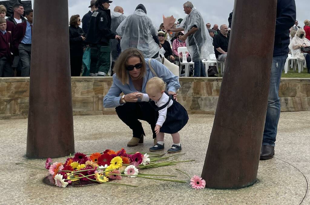 Flowers were laid at the Bali Memorial Sculpture in Coogee following the official service. Many laid their flower then touched or embraced their sculpture in honour of their lost loved one. Picture by Nadine Morton