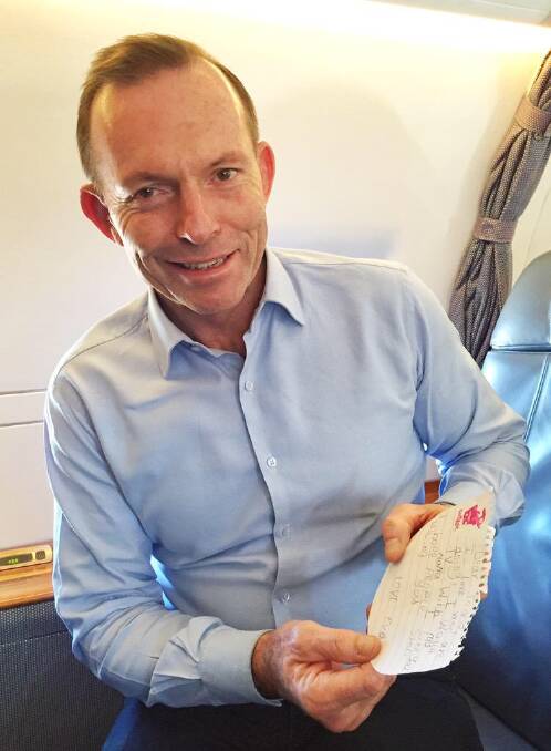 Prime Minister Tony Abbott reads a note handed to him during a visit to Warrnambool. Picture: Twitter