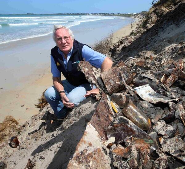 Port Fairy resident John Bade beside some of the long-buried rubbish now being exposed by erosion on the town’s popular East Beach.