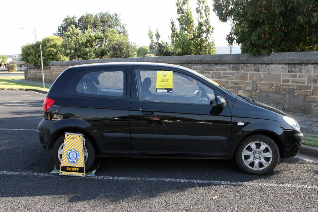 A car’s wheel is clamped in Spence Street, Warrnambool, during an operation by the sheriff’s office