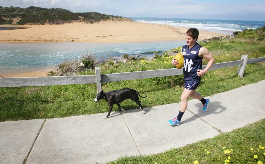 Warrnambool footballer Liam Hoy, 16, runs with his dog Baz at the Hopkins River mouth ahead of this weekend’s grand final.