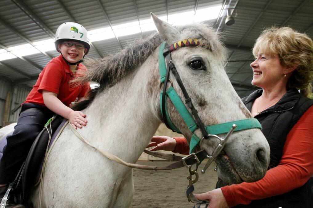 Thomas McKenzie, 5, from the Warrnambool Special Developmental School takes part in the riding for the disabled section, with volunteer Brenda Hetherington lending a hand. 