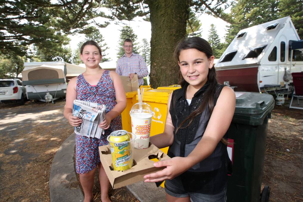 Bianca Grima, 11, (left), and Taylah Ambrus, 11, both of Geelong, seek out the recycle bin at Surfside Holiday Park, watched by park manager Alex Reardon. 