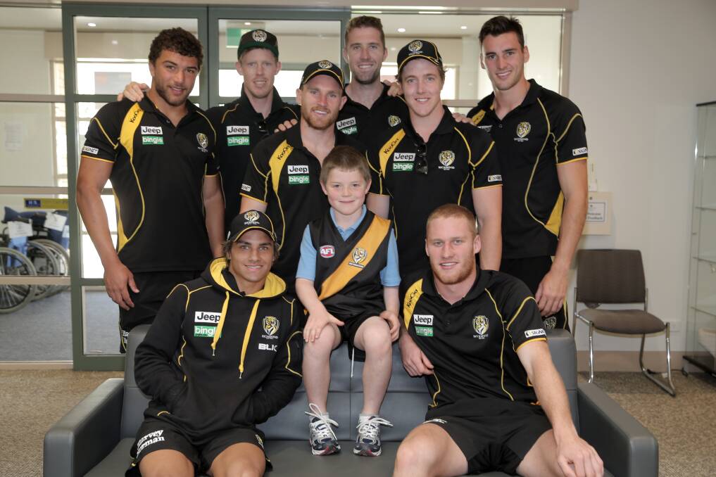 They’re from Tigerland: Richmond players gather around Charley Clancey, 7 — a diehard supporter following in his grandfather’s footsteps — during a visit to St John of God Hospital in Warrnambool yesterday. 