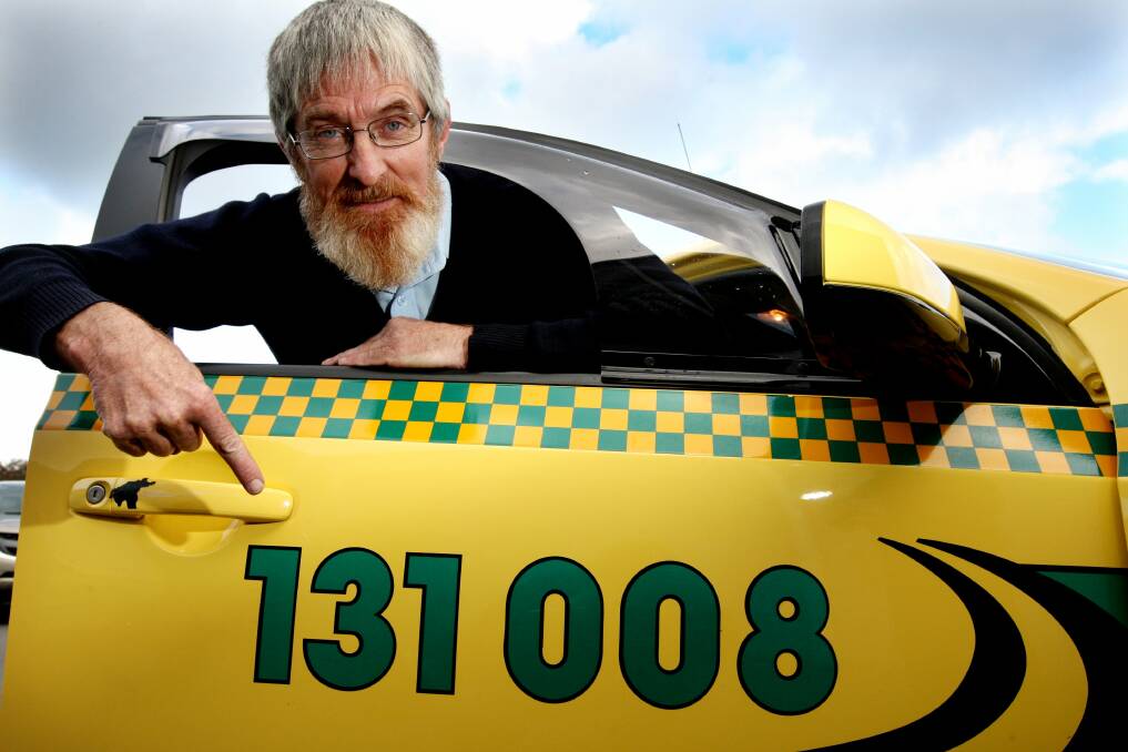 Driver John Keogh indicates Warrnambool Radio Taxis’ booking number, which won’t change as some drivers defect to a new despatch system.