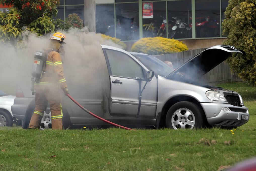 A firefighter attends to the burning Mercedes-Benz four-wheel-drive.