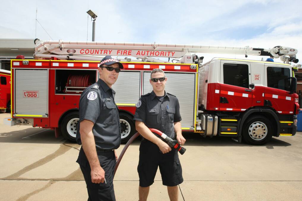 Warrnambool station officer Greg Kinross (left) and Warrnambool CFA firefighter Paul Gleeson with the still-idle aerial pumper truck.