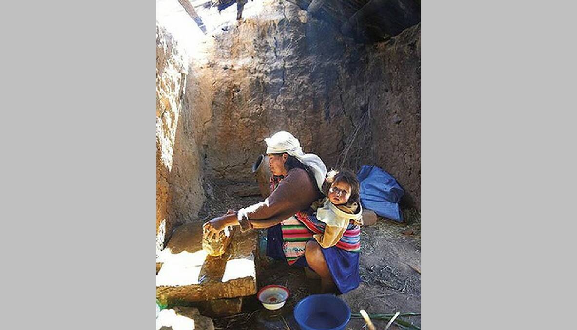 Noemi’s mother Flora prepares food with her youngest child, one-year-old Pascual, on her back. Bolivia.