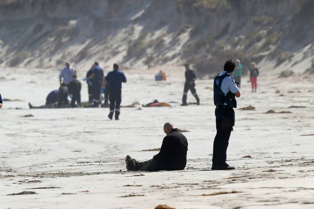 A shattered Brian Clarke sits on the beach as emergency services try to save his stepfather after Sunday’s accident. 