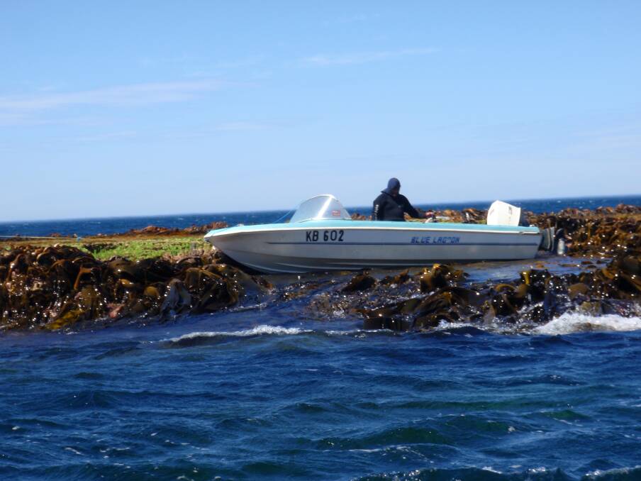 The outboard-powered boat sits high and almost dry on the reef. Picture: DAVID OWEN