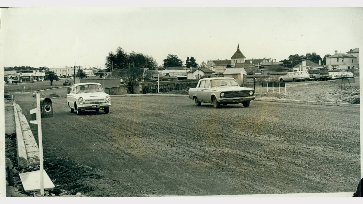 The dual highway, (now Raglan Parade) was the site of the old saleyards, but was opened for traffic in July 1970 (pictured). The stone wall along the Swan Reserve is visible in the middle of the image, with Warrnambool Primary School clear in the background. 