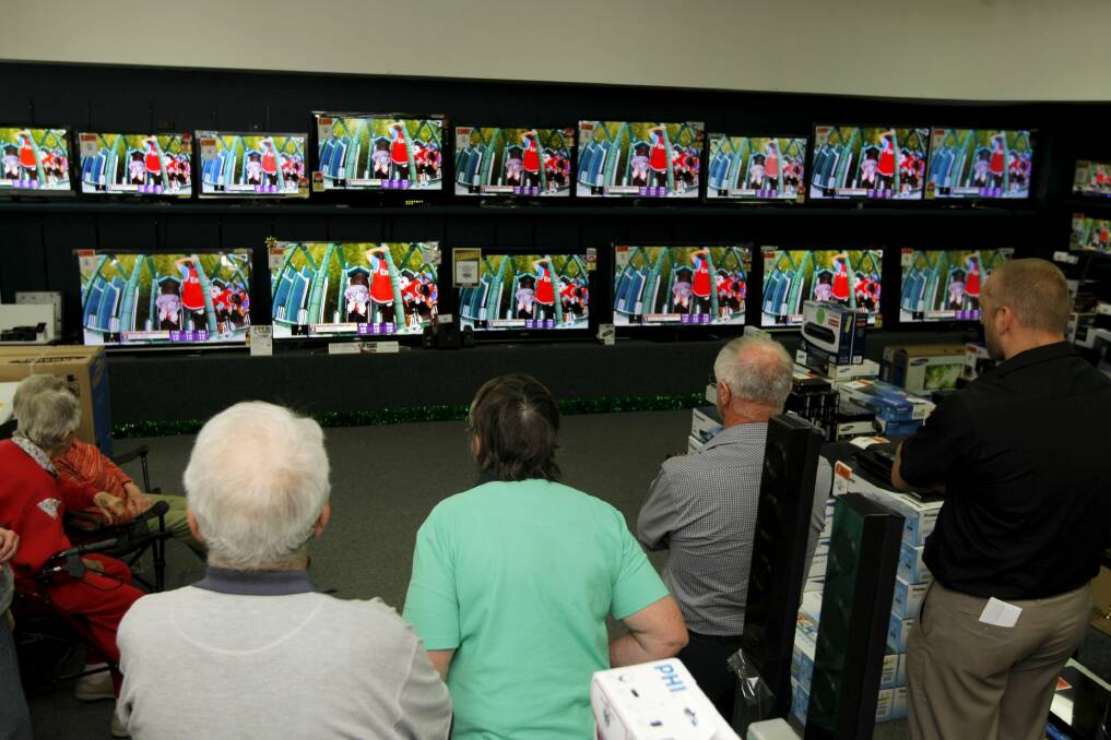 A small group of people gather at Lehy's Electricals to watch the running of the Melbourne Cup on the various screens. 