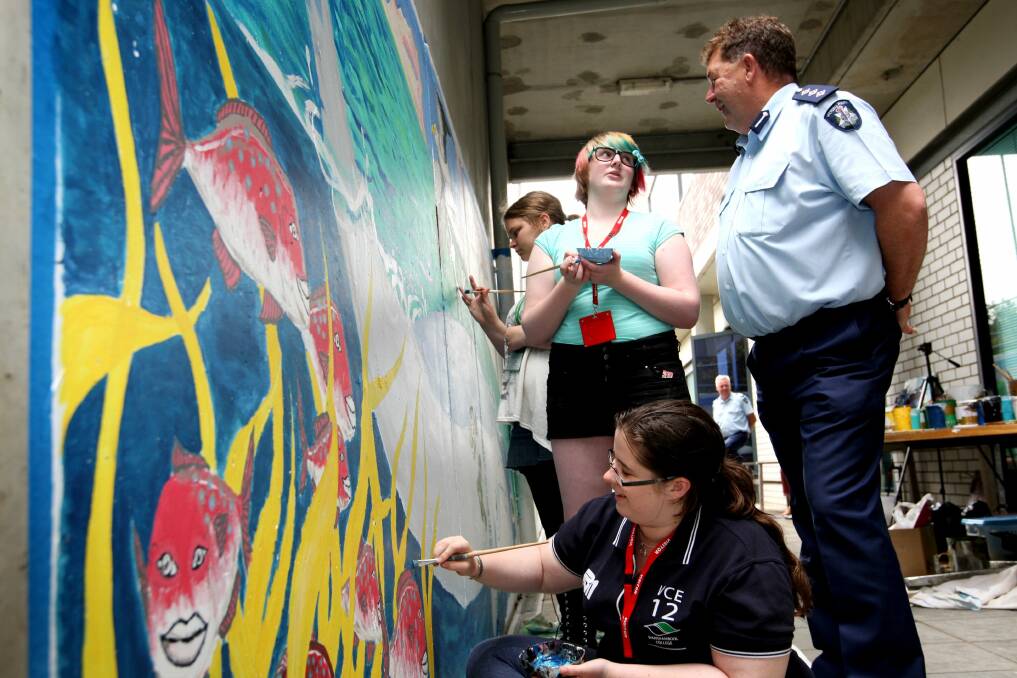 Laura McKay (front), 18, from Warrnambool, puts the finishing touches to an undersea scene with help from Jessica Vansteenbergen (back, left), 16, from Purnim, and Izzy Clark, 15 from Warrnambool, watched by Inspector Kevin Archer.