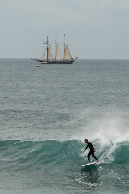 A surfer at the Passage in Port Fairy with Dutch tall ship Oosterschelde in the background . Picture:LEANNE PICKETT