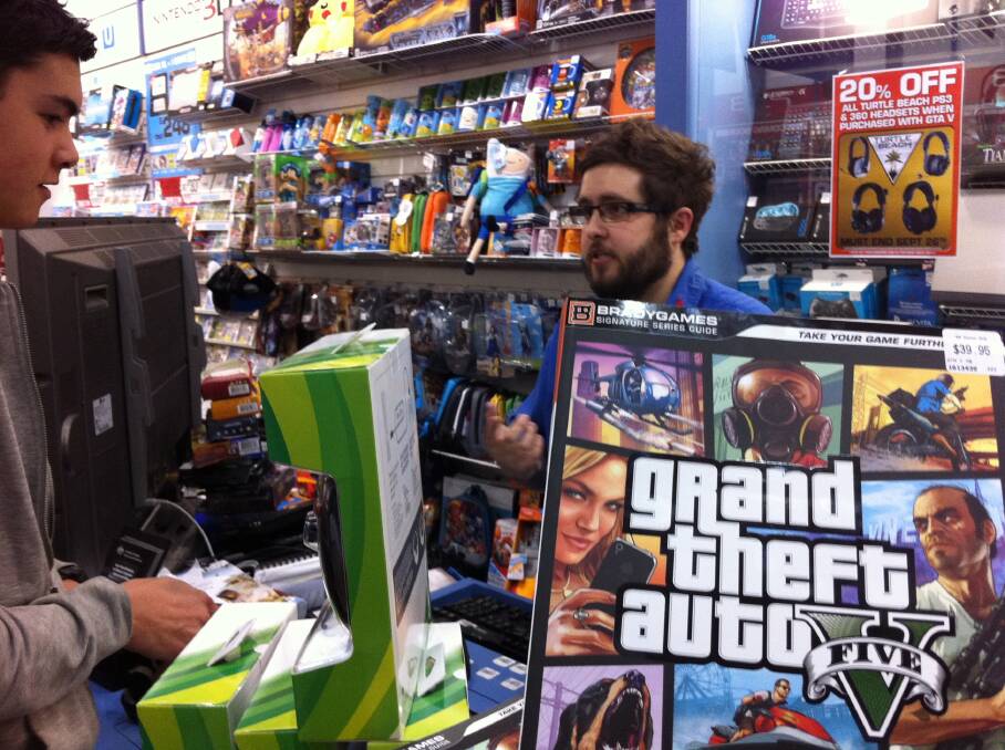 EB Games Warrnambool's Josh New serves one of the 500 customers at the midnight launch of GTA V.
